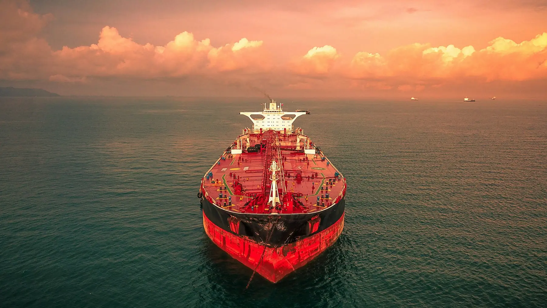 The bow of a red tanker at sea at sunrise