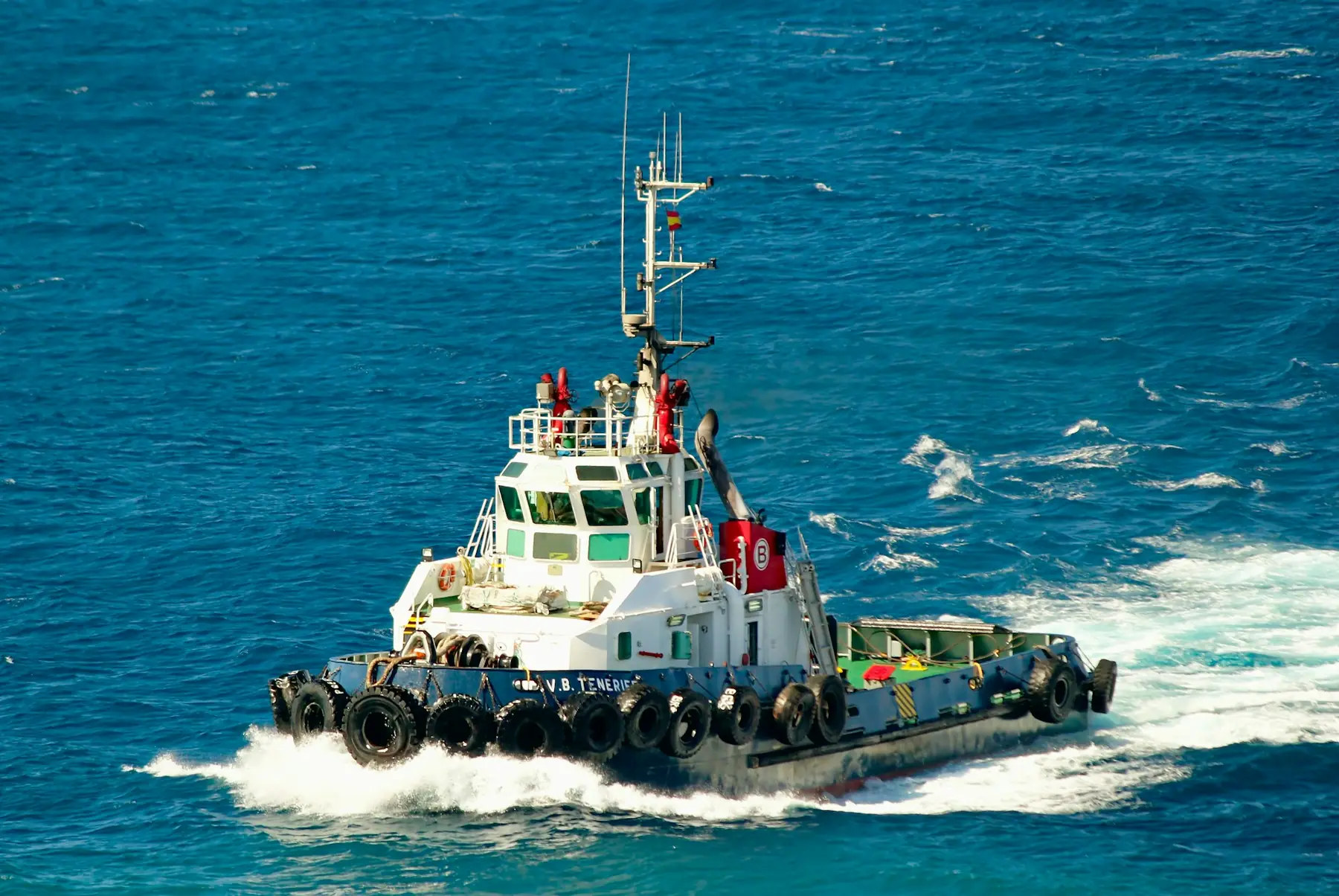 A tugboat underway with spray at the bow